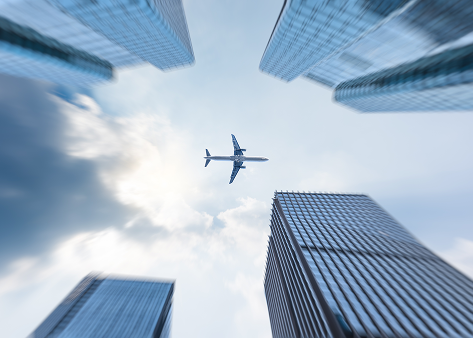 low-angle-view-business-buildings-with-plane-flying.png